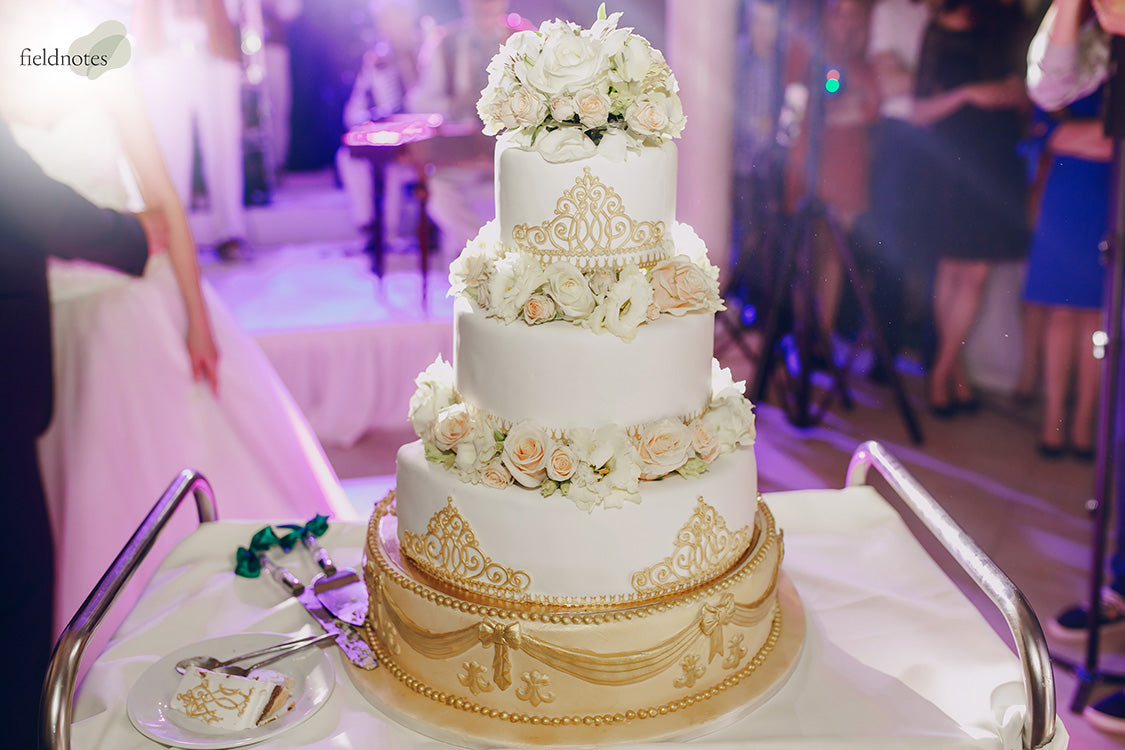 Elegant three-tier white wedding cake with gold accents and roses.