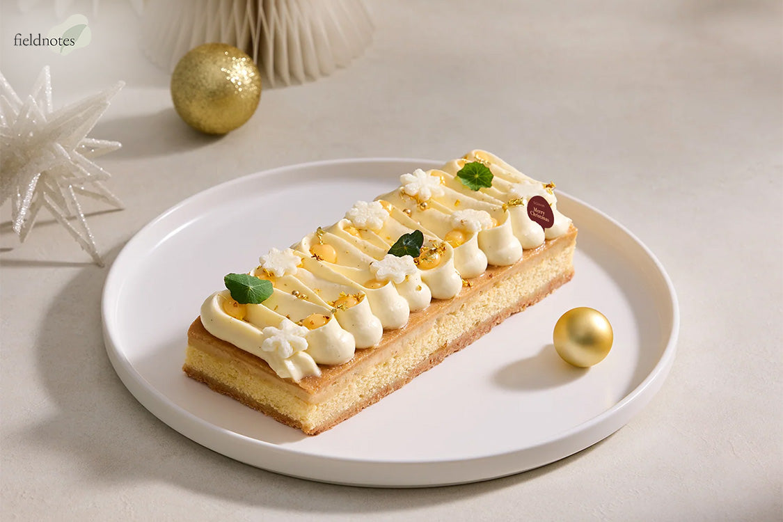 A rectangular Christmas cake topped with elegant white cream swirls