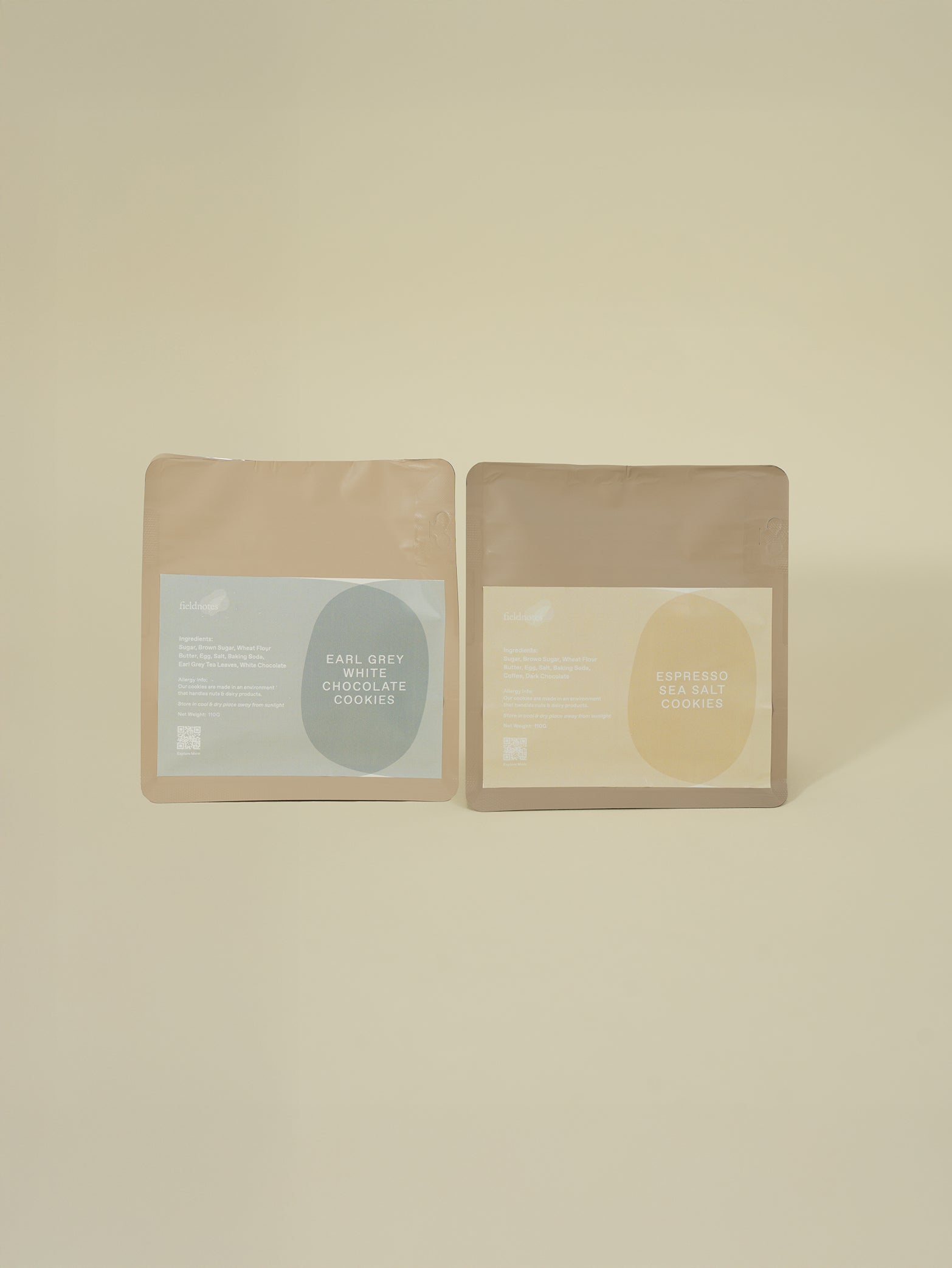 Two resealable beige pouches stand side by side, labeled Earl Grey Chocolate Cookies and Espresso Chocolate Cookies with minimalist blue and brown designs on a plain light background.