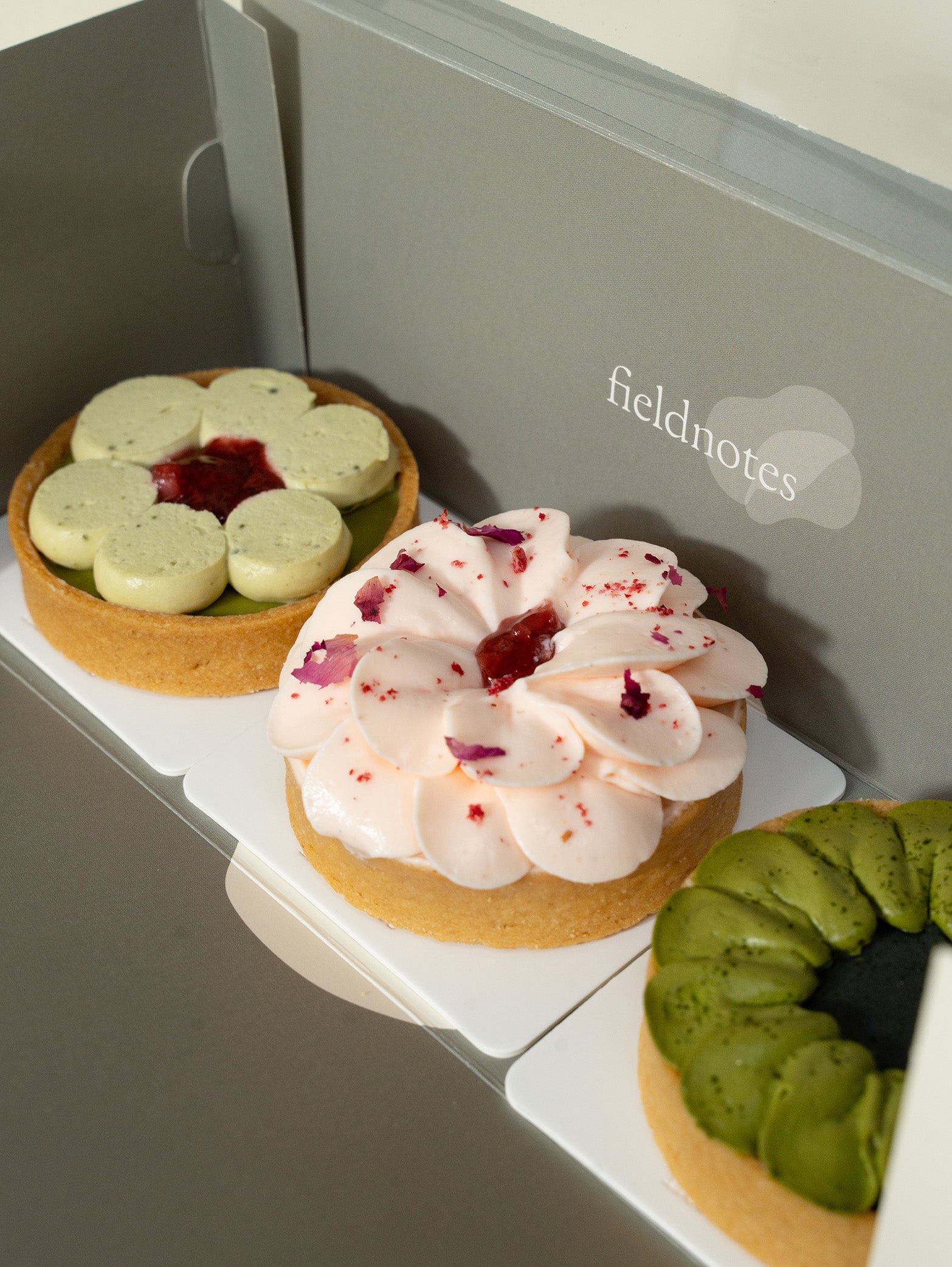 A box of three assorted tarts with a variety of fillings and toppings, including matcha green tea, strawberry, and rose flavors for online order for delivery in Singapore