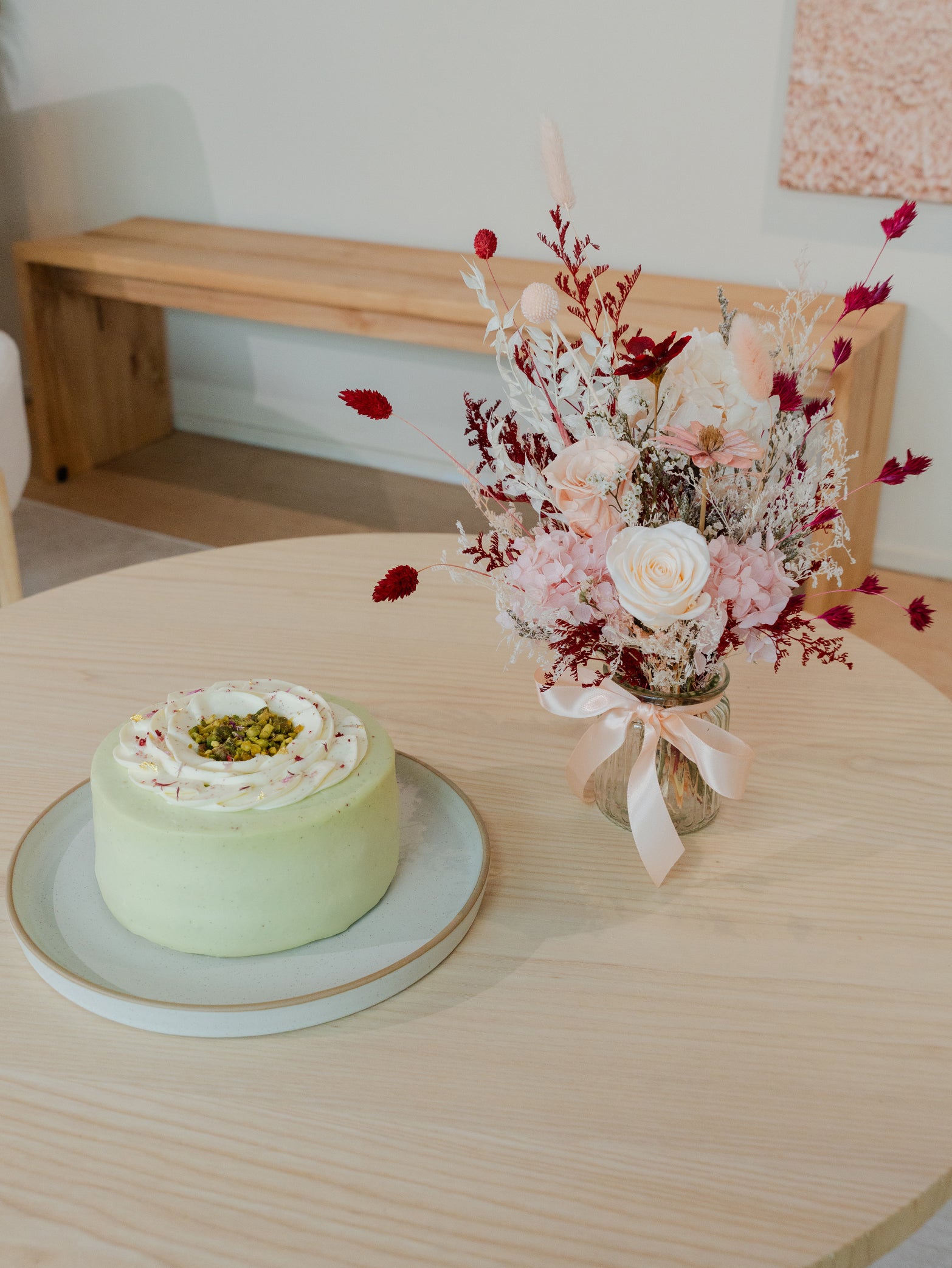 A round pistachio praline cake with a preserved rose bouquet in a vase, available for online order in Singapore for next day delivery