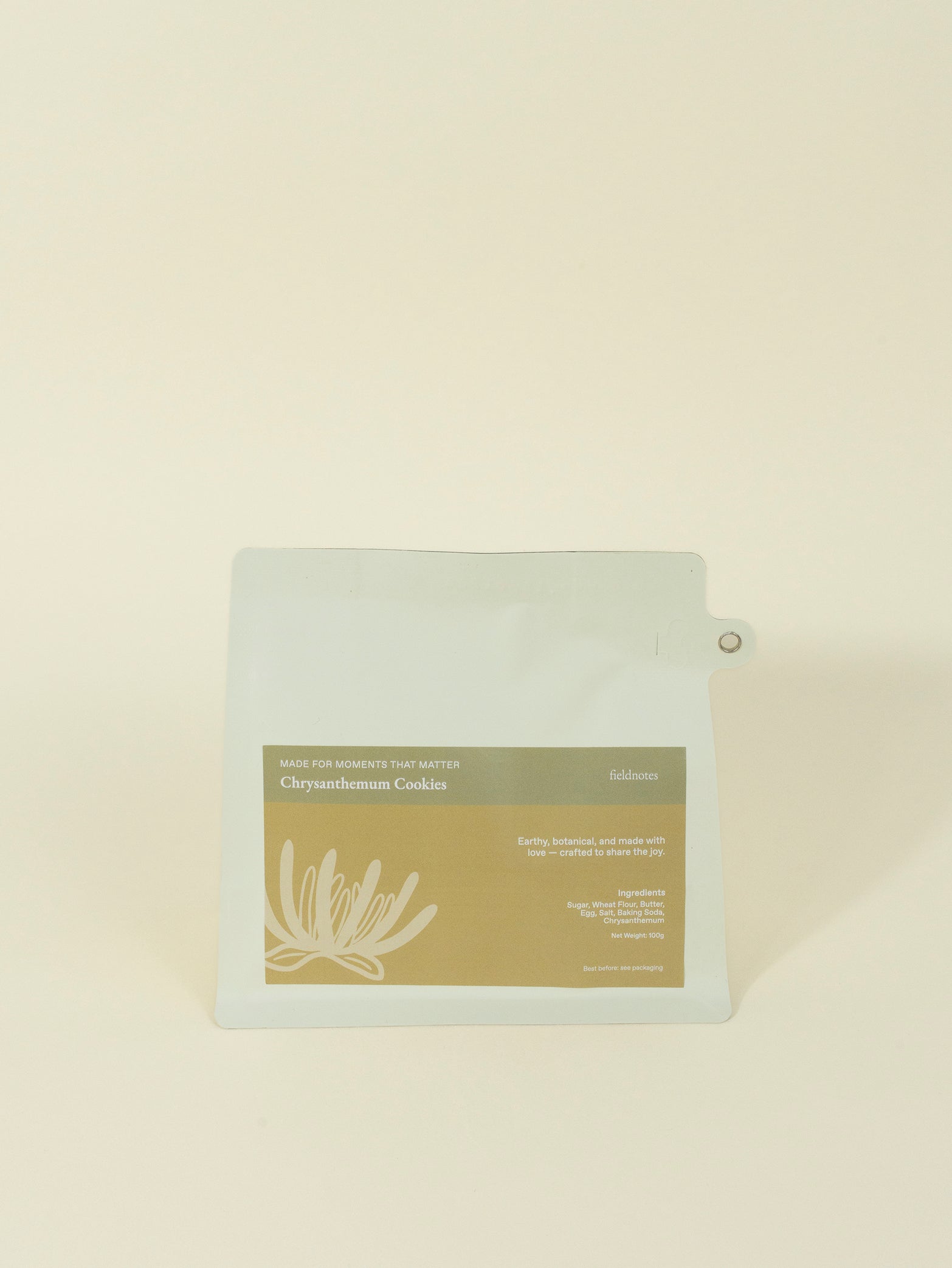 A light pouch labeled "Chrysanthemum Cookies" by fieldnotes, with a floral design, stands like a tart or birthday cake on beige.