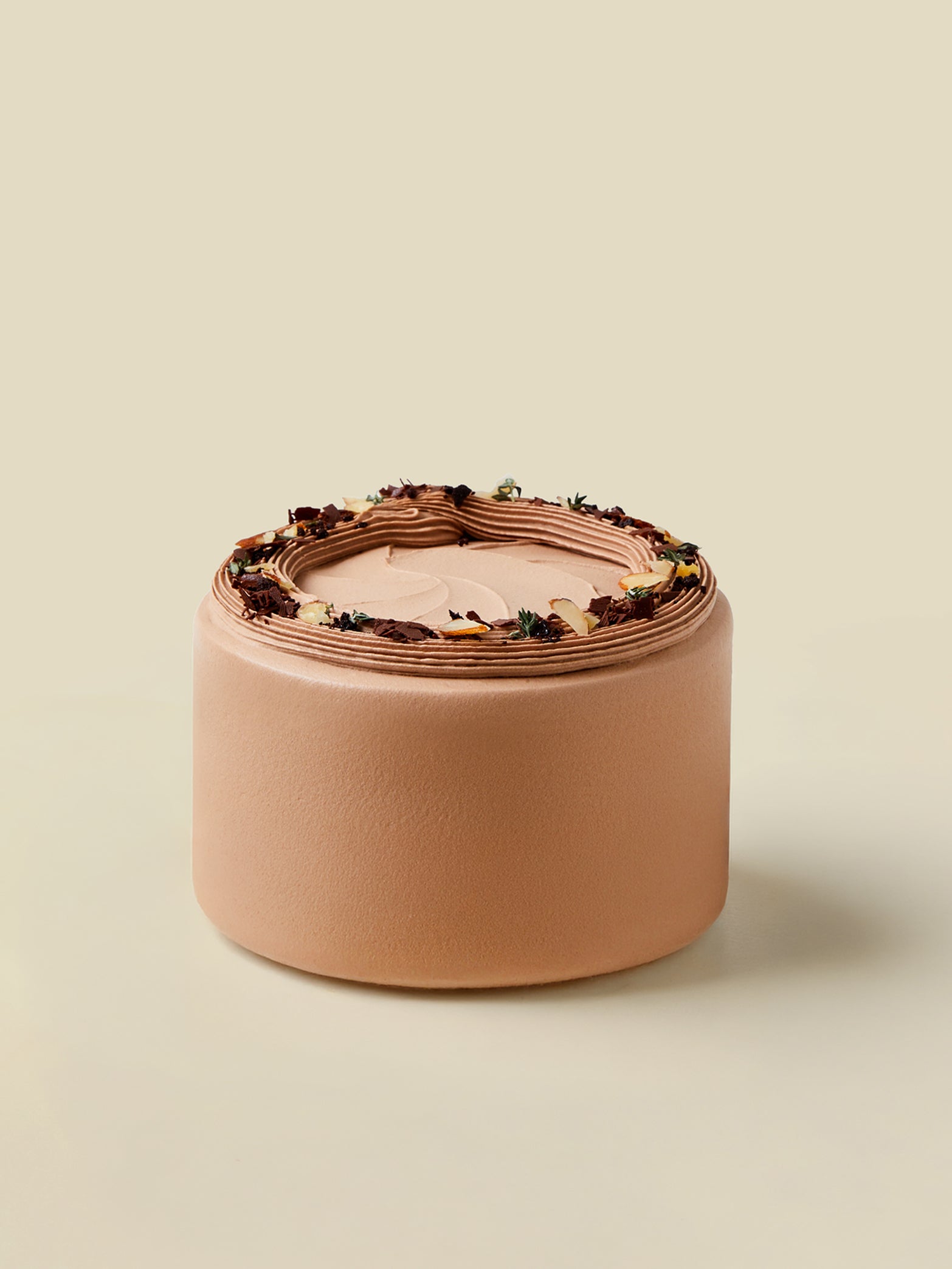 The "All Chocolate" birthday cake by fieldnotes is a round, light brown tart with ganache-frosted edges and floral accents on top.