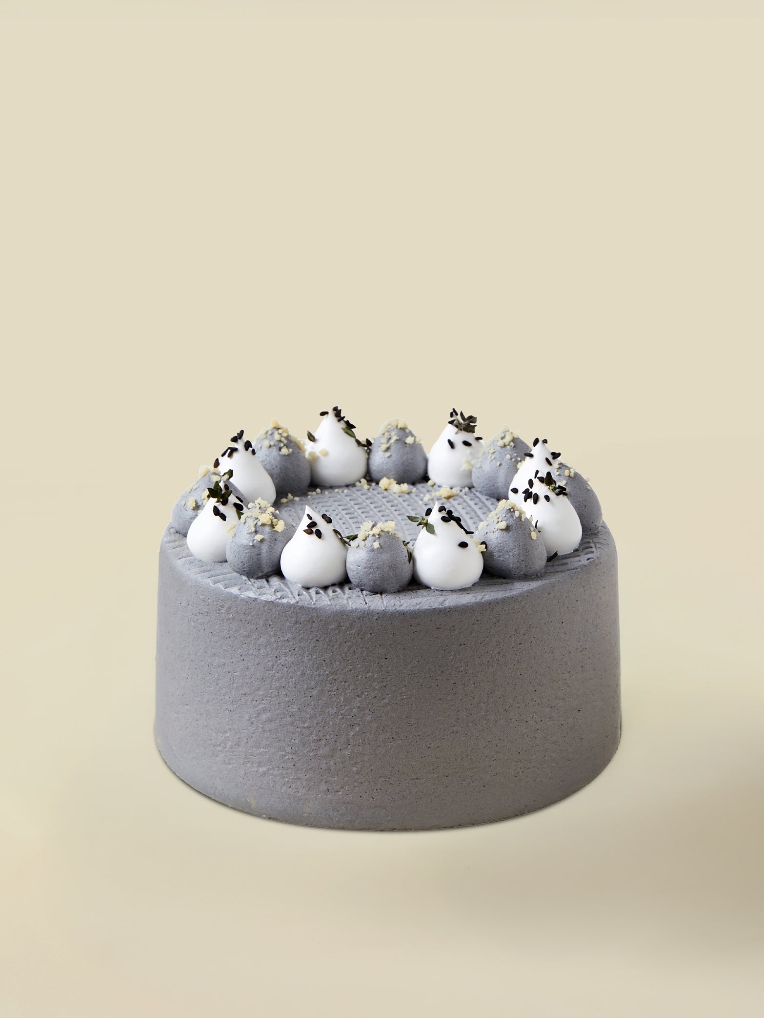 The fieldnotes Roasted Black Sesame Hōjicha birthday tart is a round, smooth grey cake topped with white and grey cream and seeds.