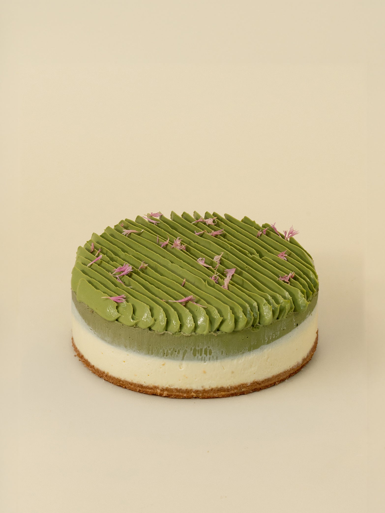 The fieldnotes Uji Matcha Cheesecake tart resembles a birthday cake, with green frosting, white layer, brown base, and purple flowers.