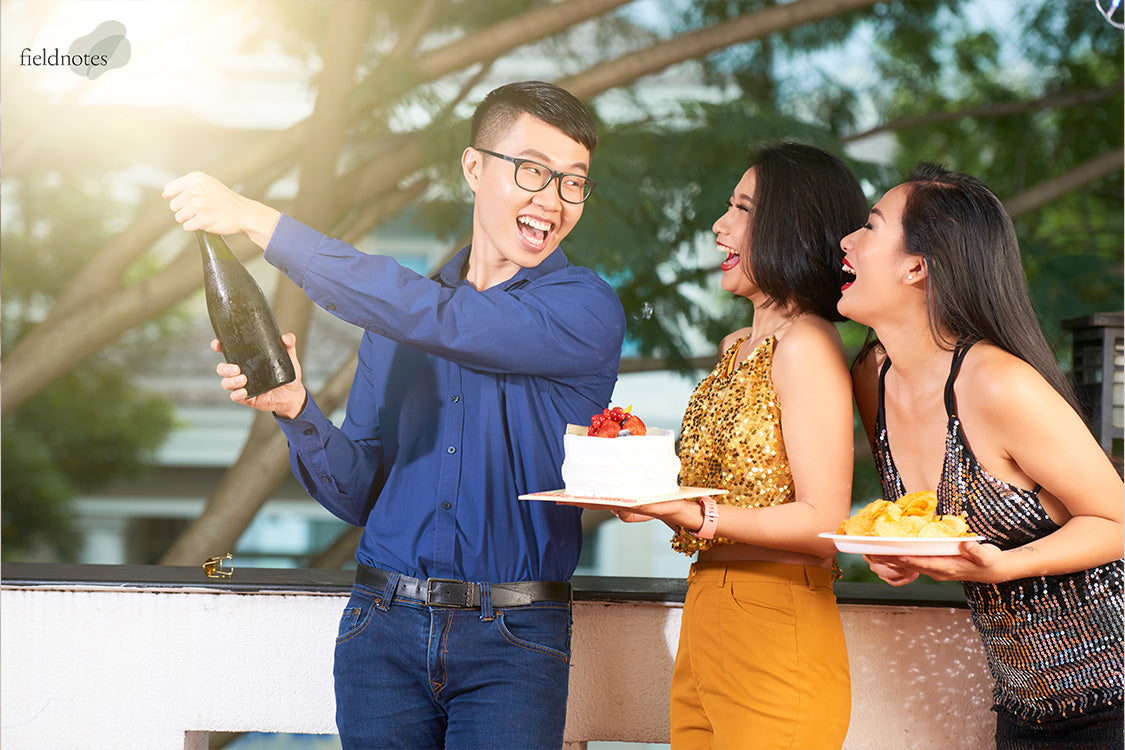 A group of friends laughing and celebrating with champagne and a fresh cream celebration cake