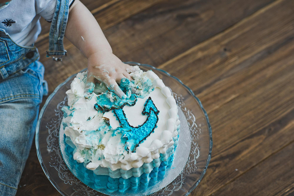 Baby smashing a nautical-themed first birthday cake