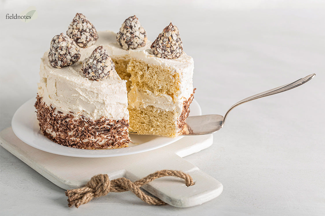 A vegan vanilla layer cake, with a slice being removed.