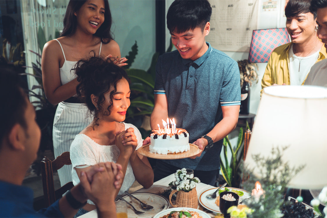 A woman sitting in front of a cake with lit candles