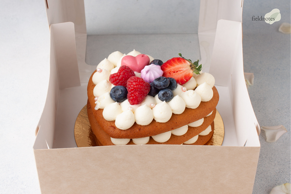 Heart-shaped berry cake secured in a box.