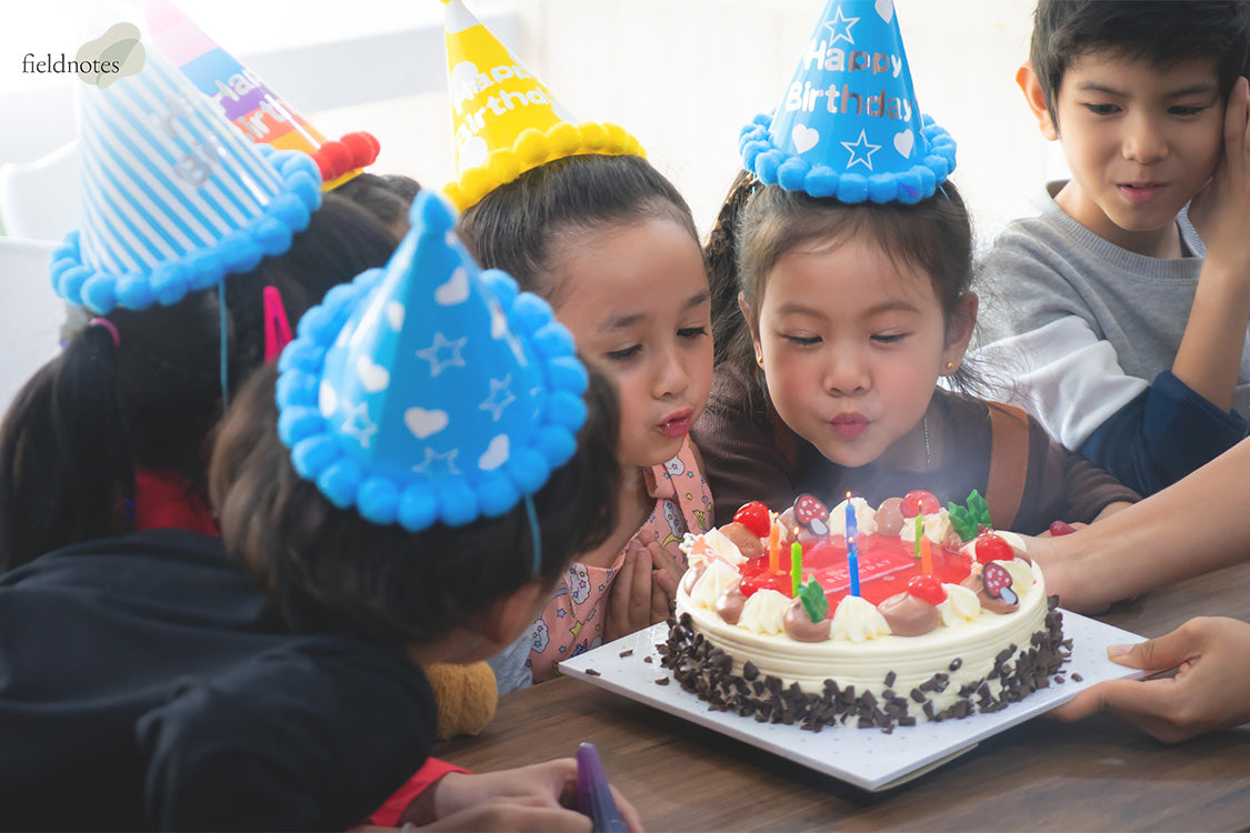 Kids blowing candle on a birthday cake