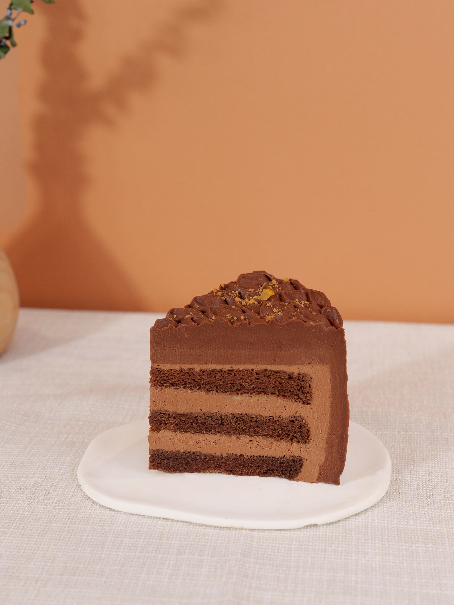 A slice of fieldnotes Yuzu Caraïbe 66% Chocolate tart with chocolate frosting and nut topping rests on a plate—ideal as a birthday cake.