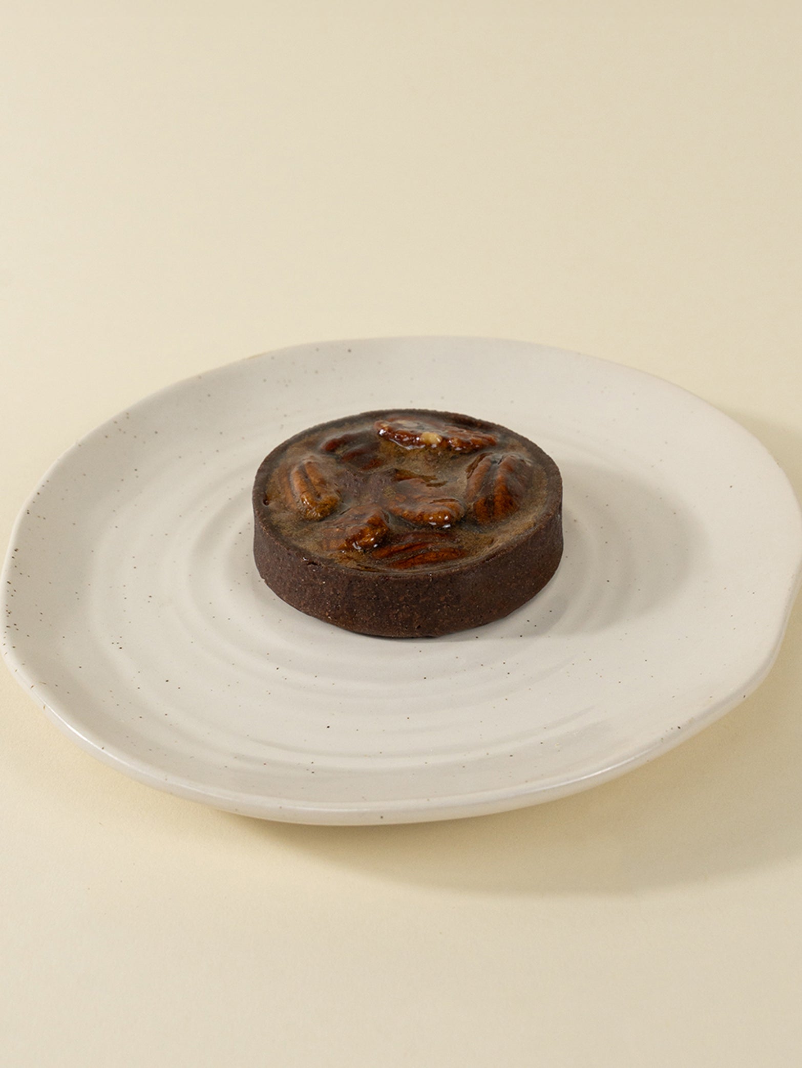 Fieldnotes’ Golden Pecan Tart (8CM box of 3), like a birthday cake, sits on a white plate with its golden-brown crust showcased.