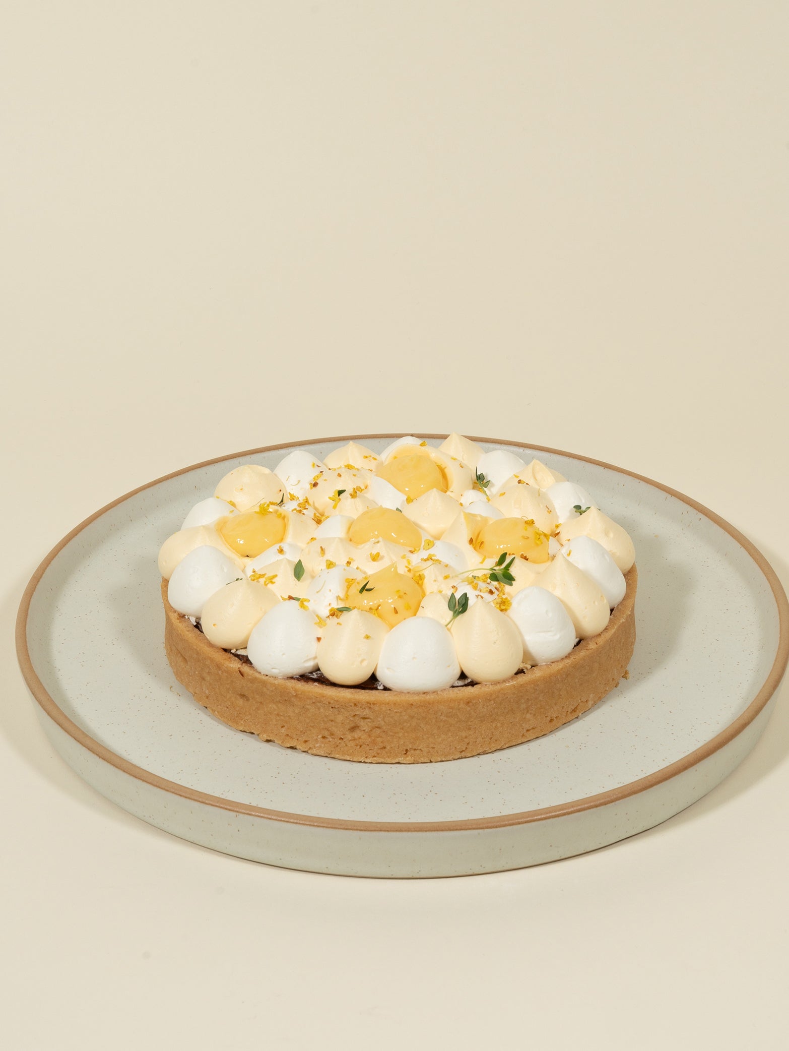 The fieldnotes Chocolate Yuzu birthday tart, with golden crust and creams, is served on a light gray plate against a beige background.