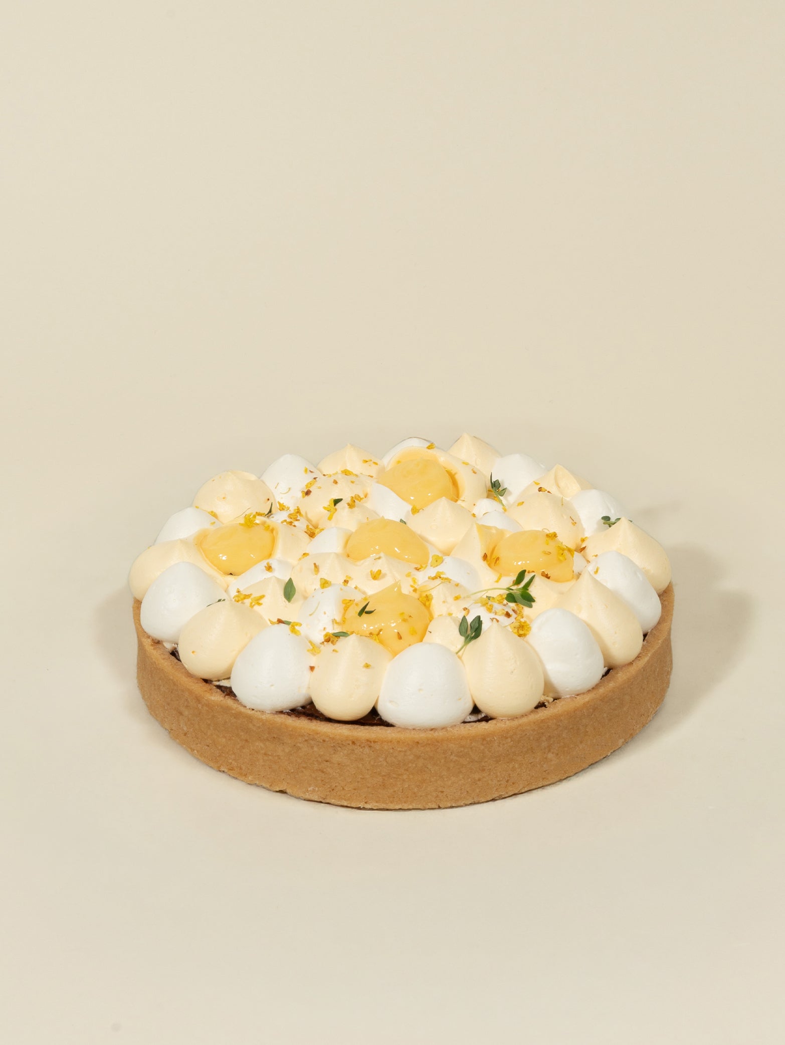 The fieldnotes birthday tart features a golden crust, fluffy chocolate and yellow meringue, citrus yuzu peel, and green herbs.