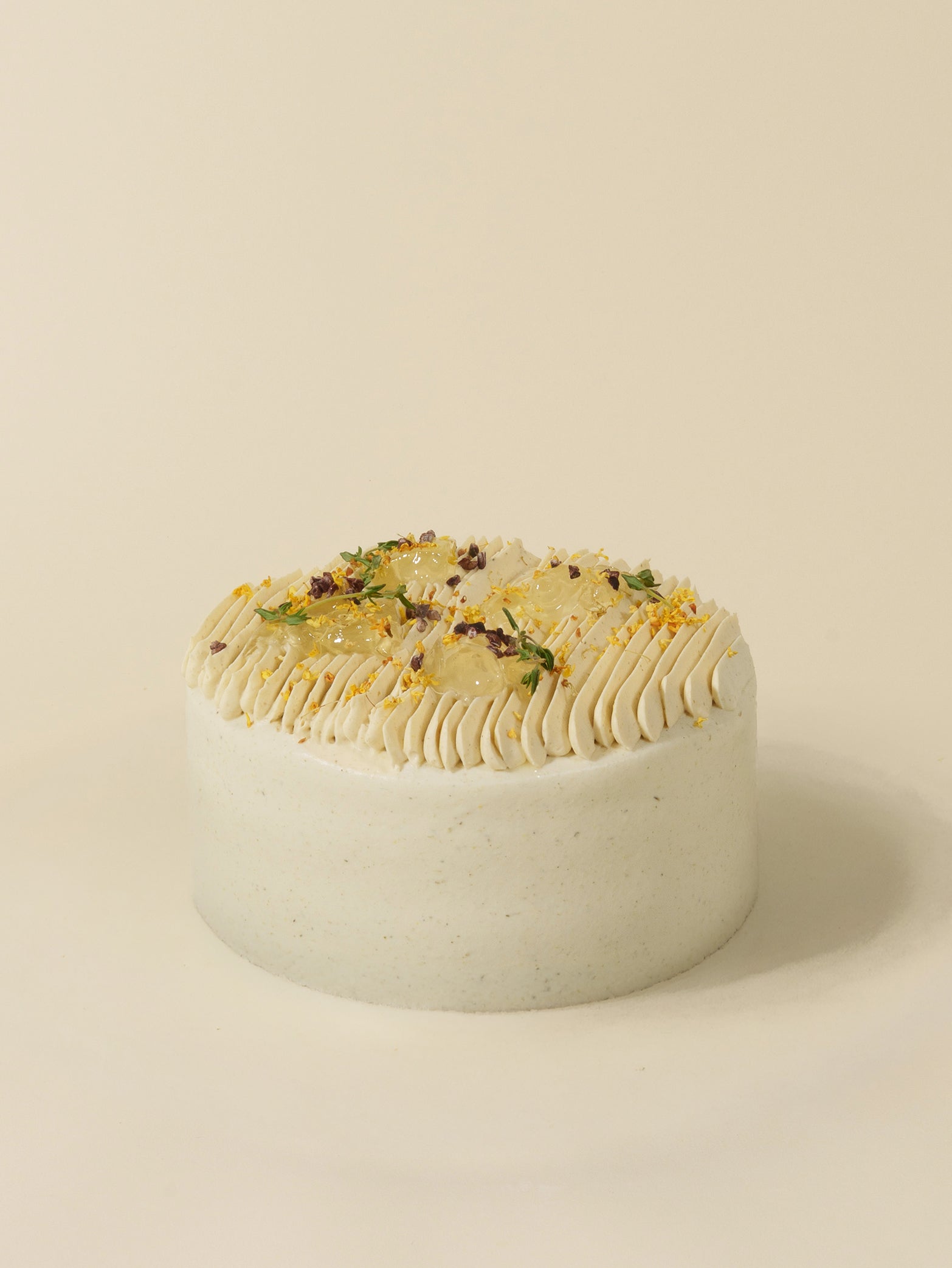A round, white-frosted birthday cake by fieldnotes, styled like a Chrysanthemum tart with colorful cream swirls and garnishes.