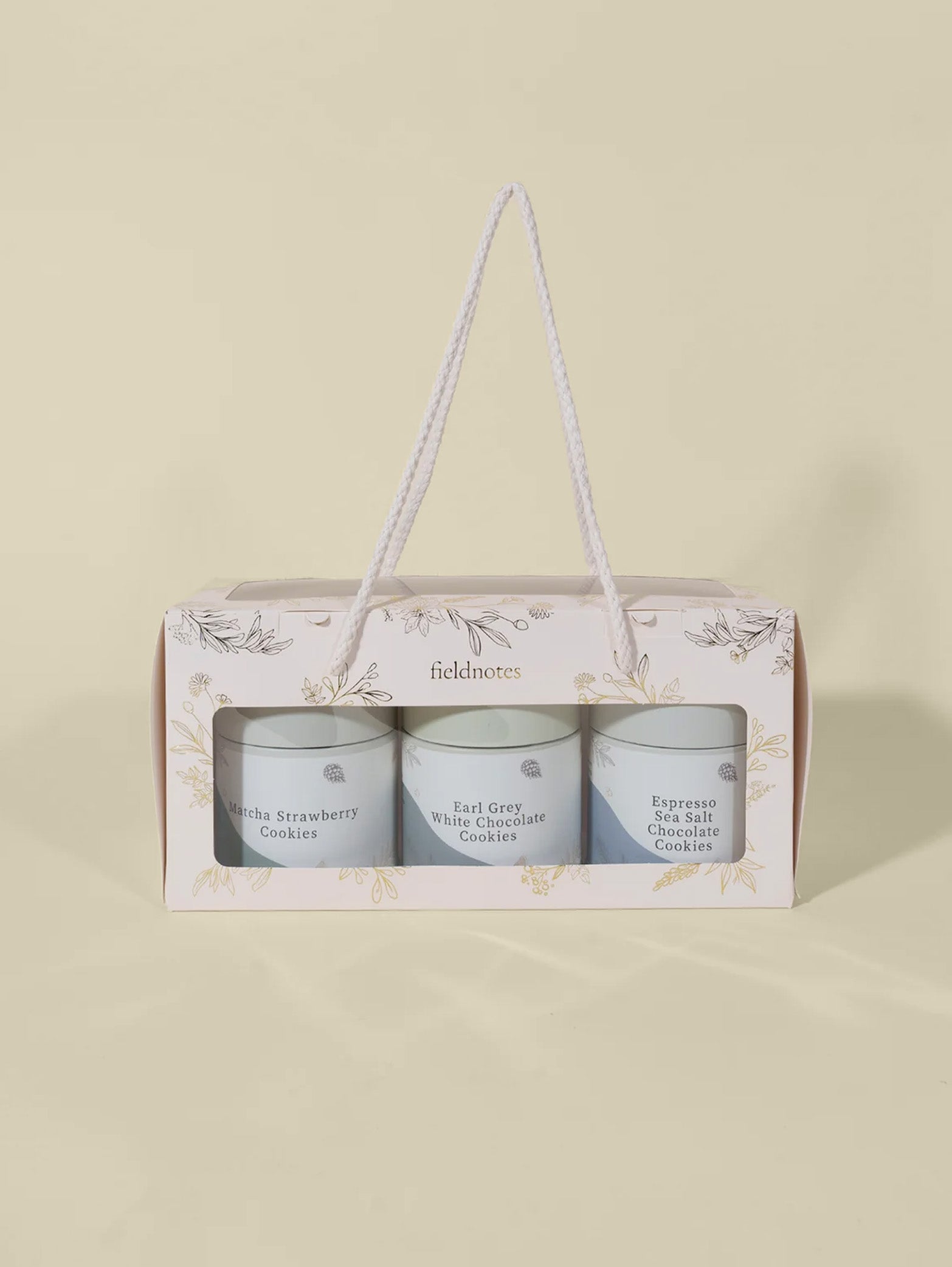 The Days of Wonder | Assorted Cookies Set by fieldnotes features three jars—Matcha Strawberry, Earl Grey White Chocolate, and Espresso Sea Salt Chocolate—like a birthday cake or tart selection—in a white handled gift box against a light beige background.