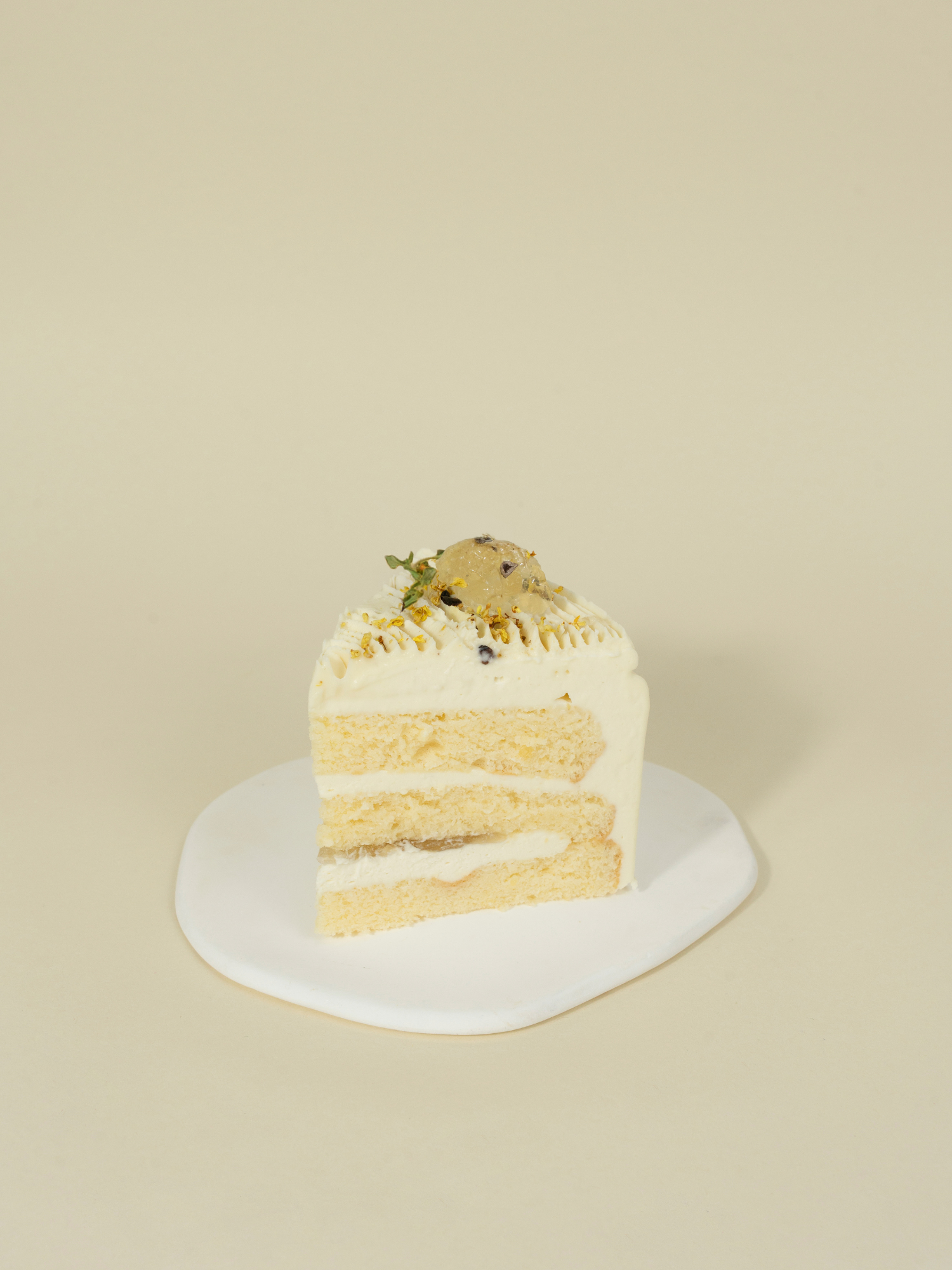 A slice of fieldnotes' Chrysanthemum Bloom birthday cake or tart with layers, white frosting, and ice cream sits on a white plate.