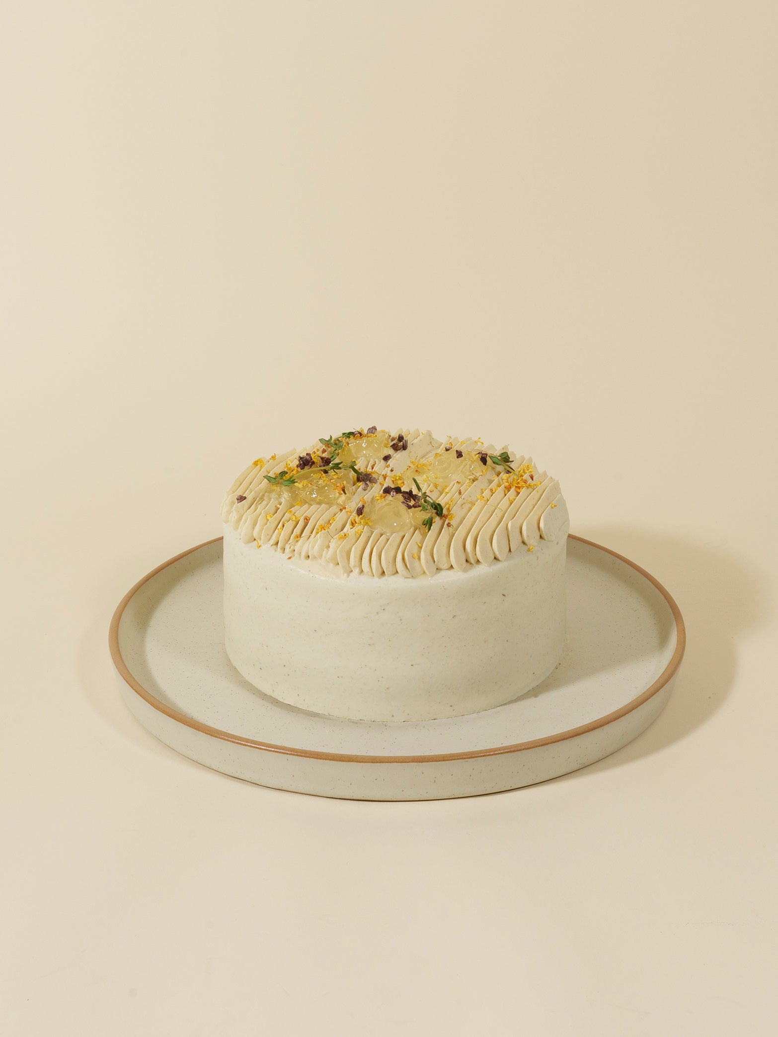 The fieldnotes Chrysanthemum Bloom birthday cake is round with smooth white frosting, piped edges, and colorful dried flowers on top.