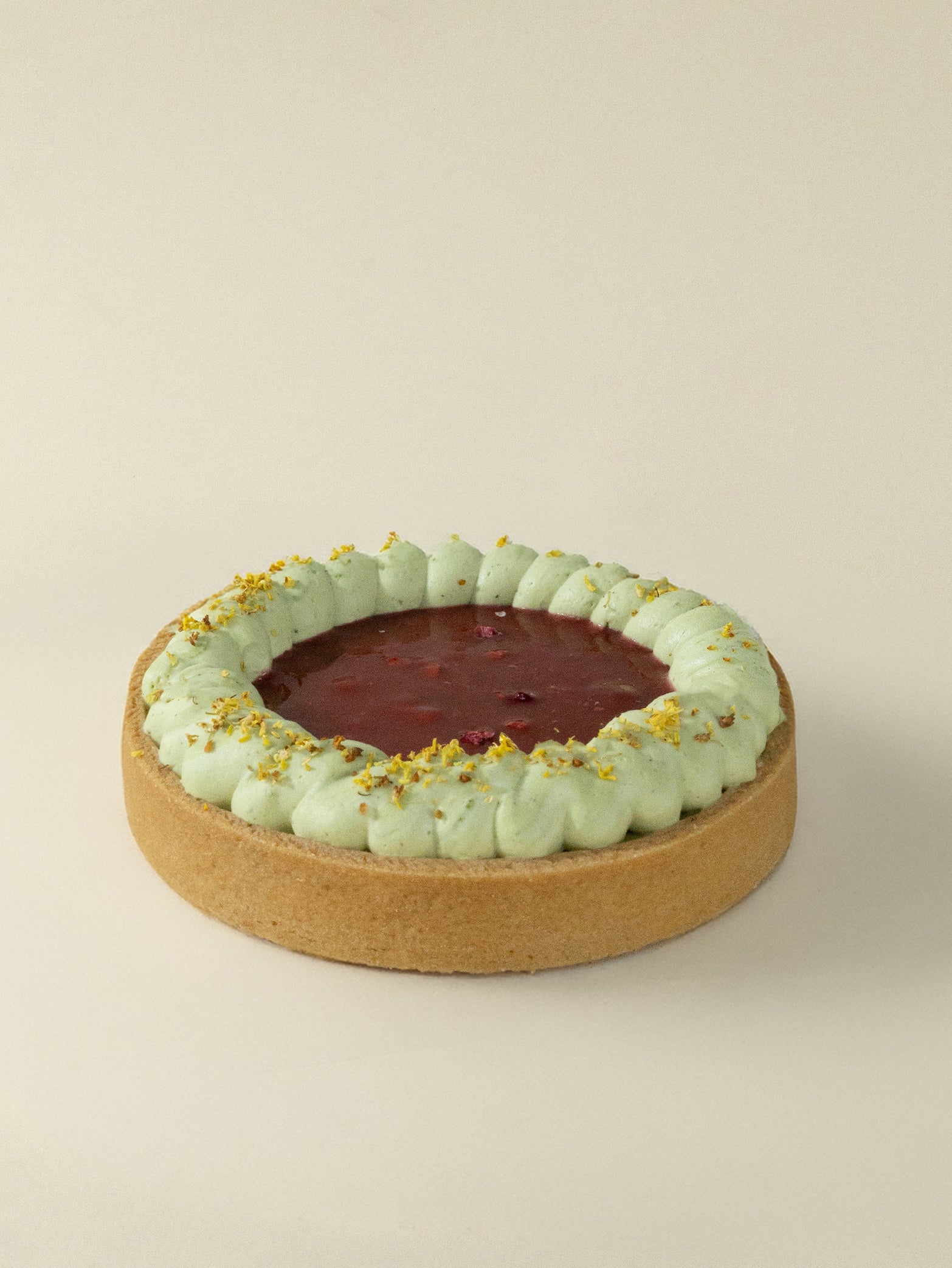 The fieldnotes Raspberry Pistachio Tart resembles a birthday cake with golden crust, raspberry filling, green cream, and pistachio praline.