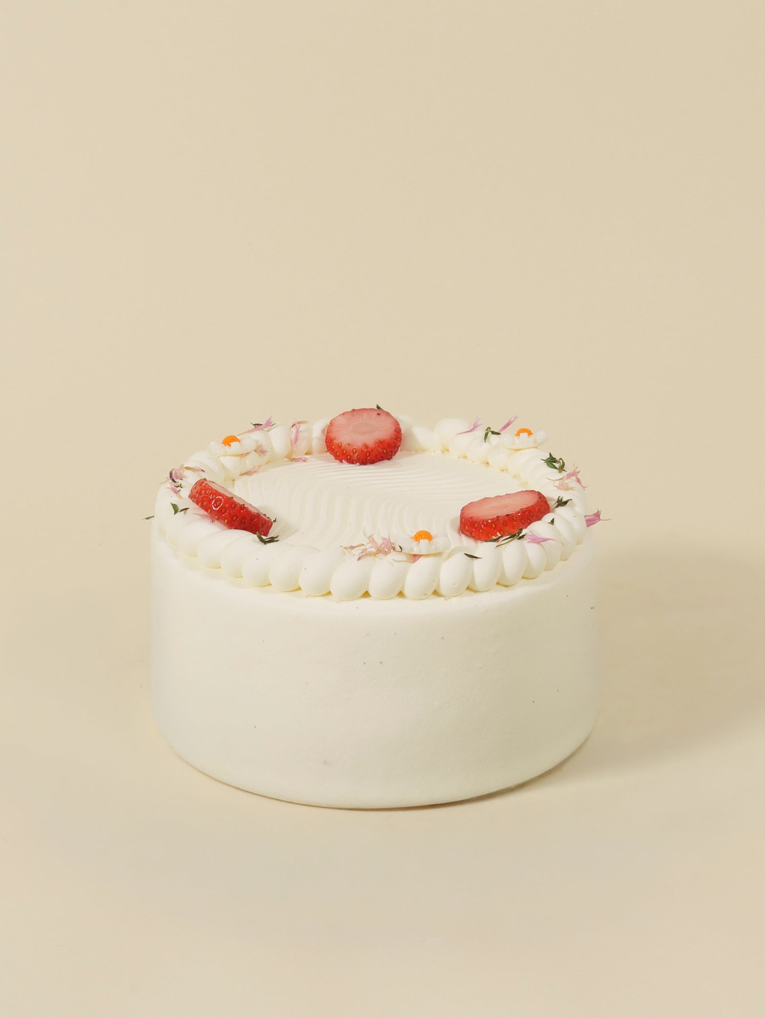 The fieldnotes Strawberry Shortcake birthday cake has vanilla sponge, chantilly cream, strawberries and flowers—cake tart on beige.