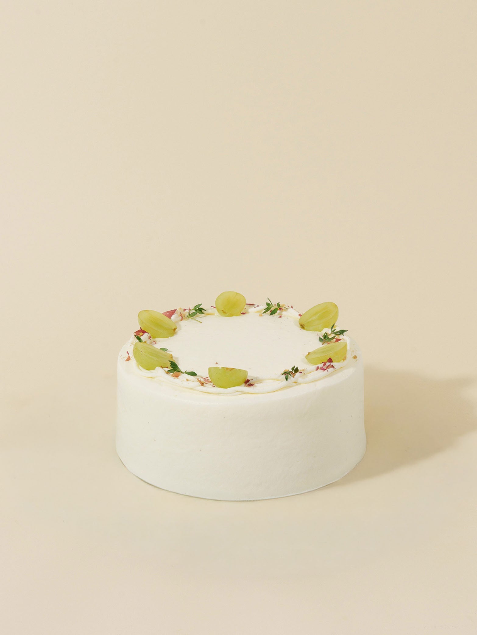 The Jasmine Grape by fieldnotes is a round birthday cake or tart topped with halved green grapes and small green leaves on beige.