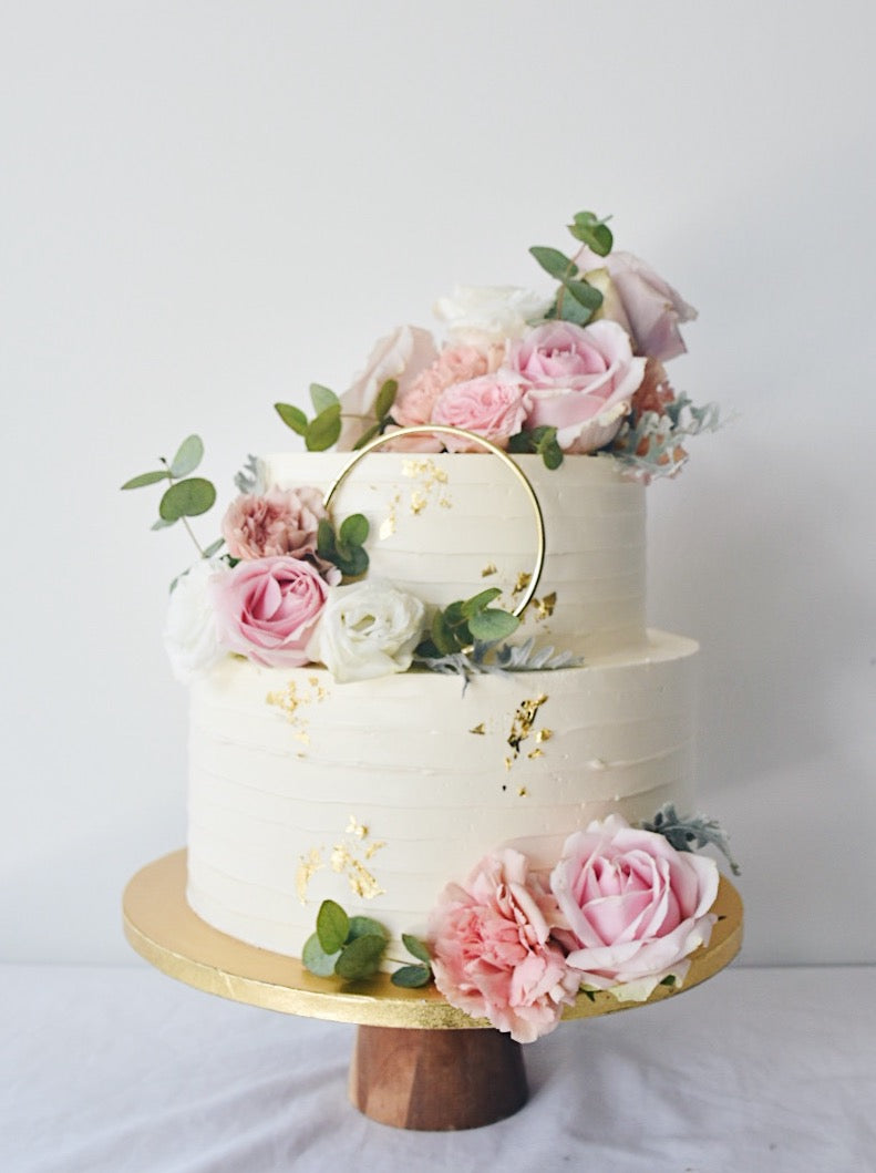Two tier white cake with gold foil and pink flowers with gold ring-zeeandelle 